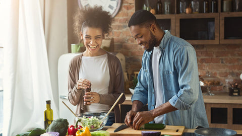 A young couple having fun together while preparing a healthy meal.