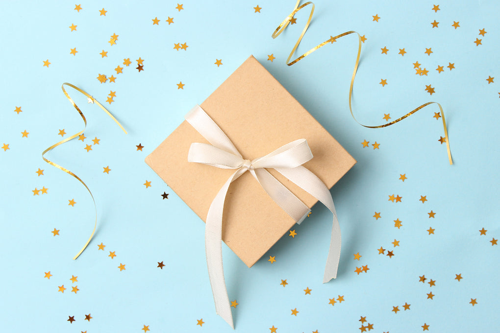 A beige present placed on a pale blue background to announce the birthday sign-up for customers. 