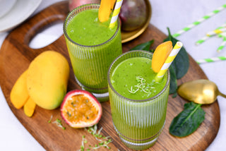Two glasses filled with a healthy, green mango-microgreen smoothie, topped with fresh ingarden microgreens.