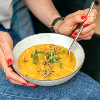 ingarden customer presenting her bowl of red lentil soup topped with fresh ingarden microgreens.