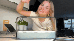 Young woman pressing the timer button of her ingarden and afterwards touching the full-grown microgreens.
